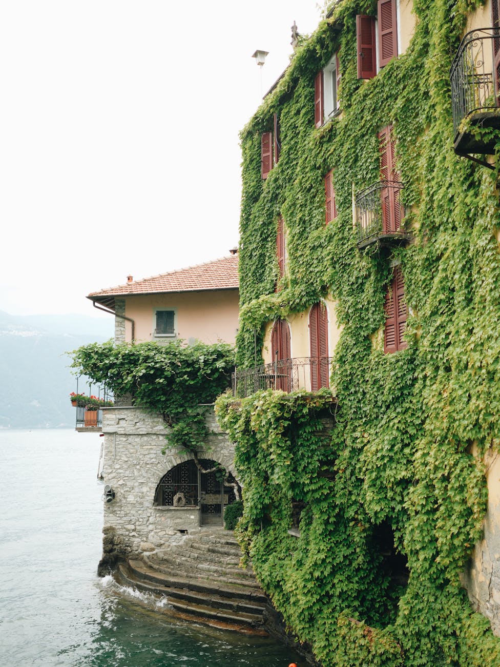 a house with vines growing on it by the water, orrido di nesso, italy